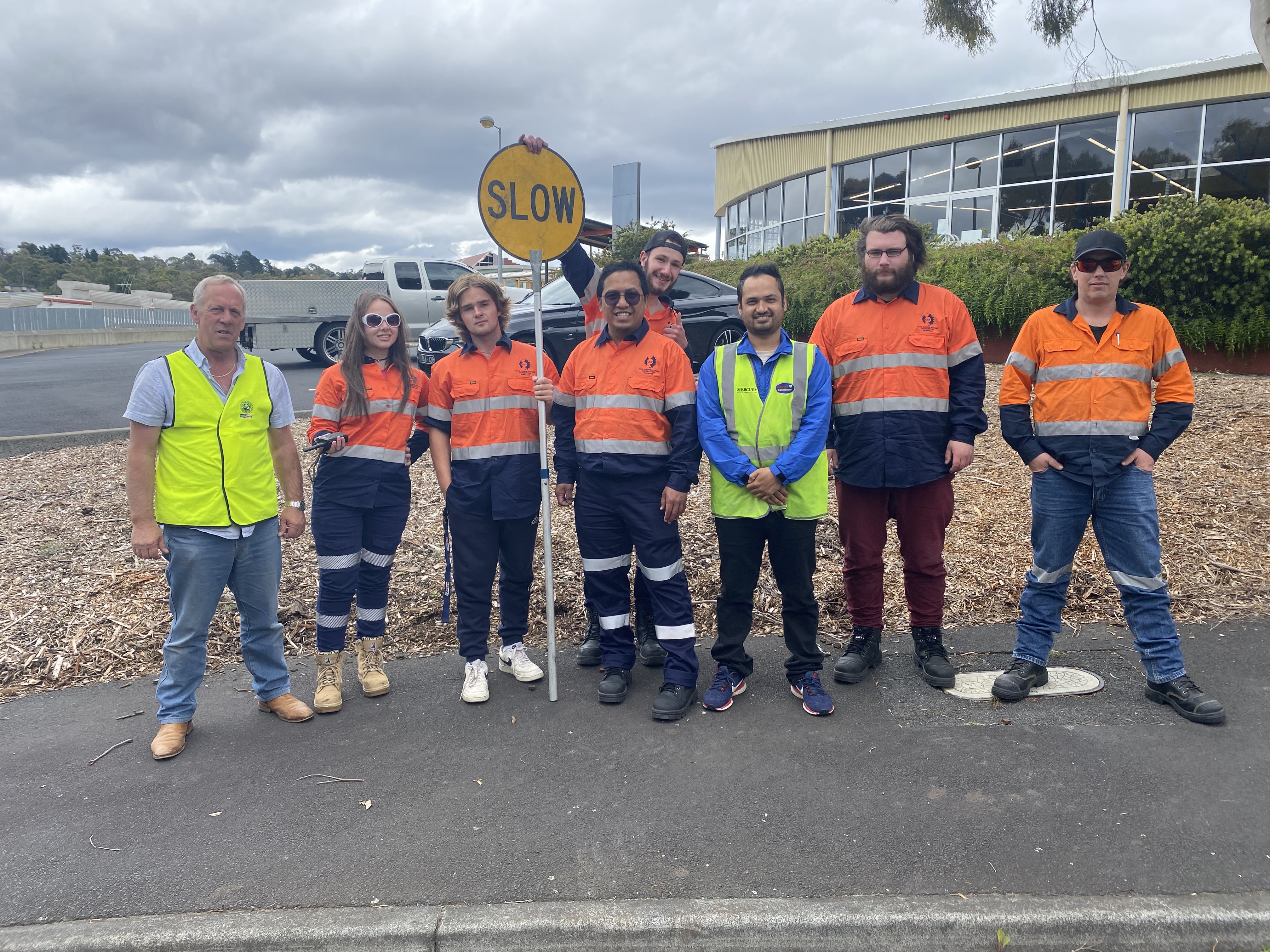 8 people standing around a slow lollipop sign