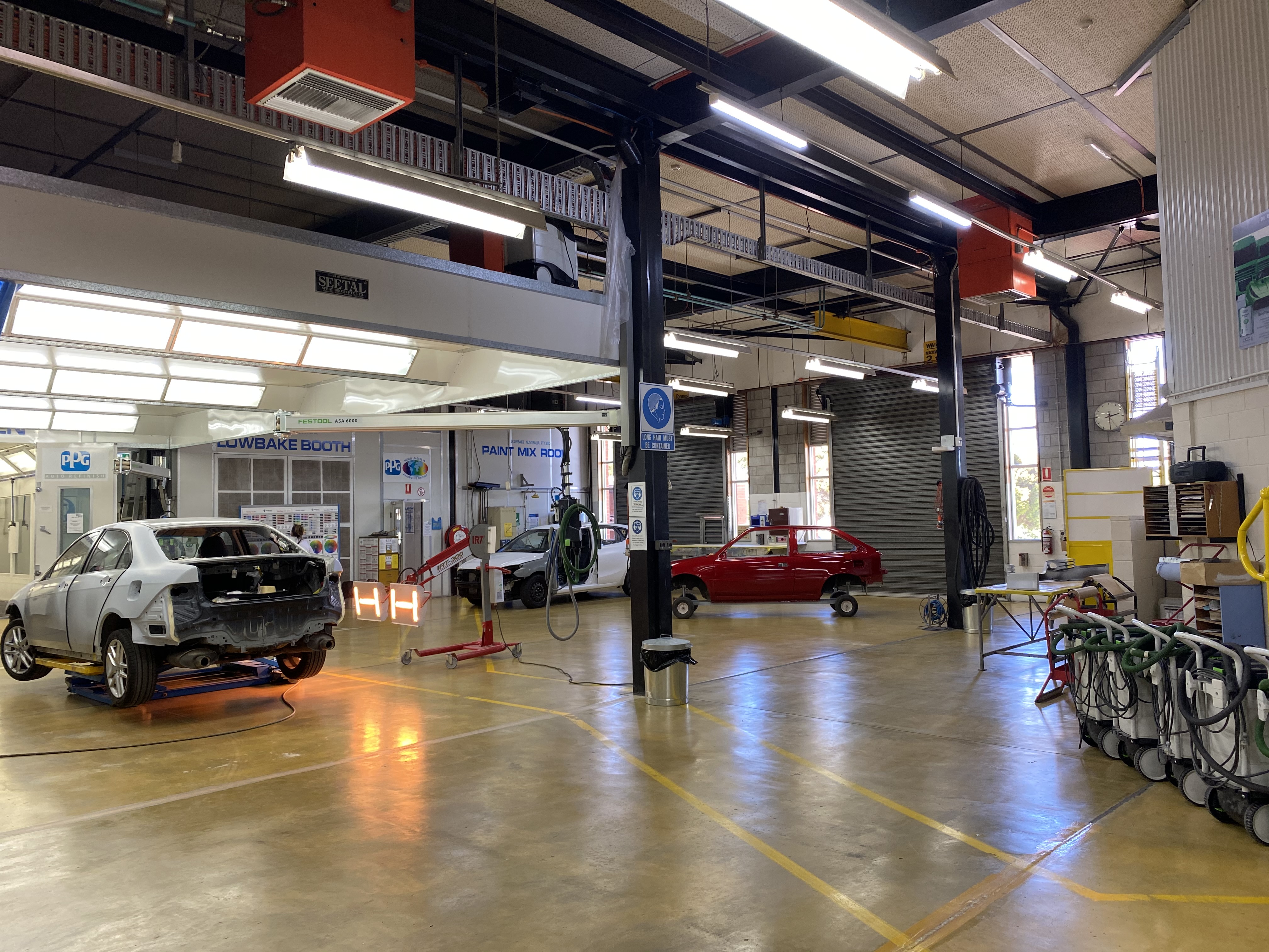 Automotive workshop with cars on  jacks and spray paint booths in the background