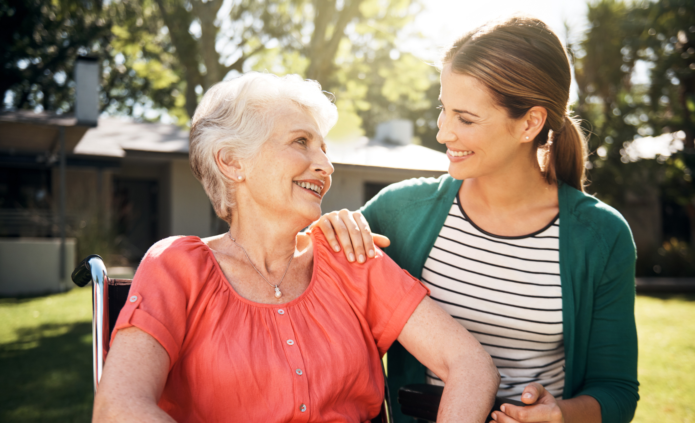 Aged care worker with an elderly female in a wheelchair outside