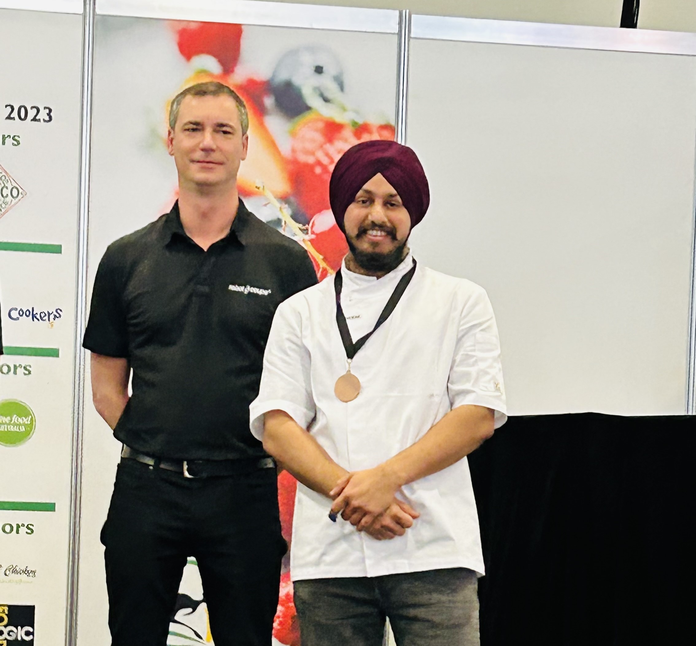 Lovepreet Singh with a medal around his neck standing with his teacher