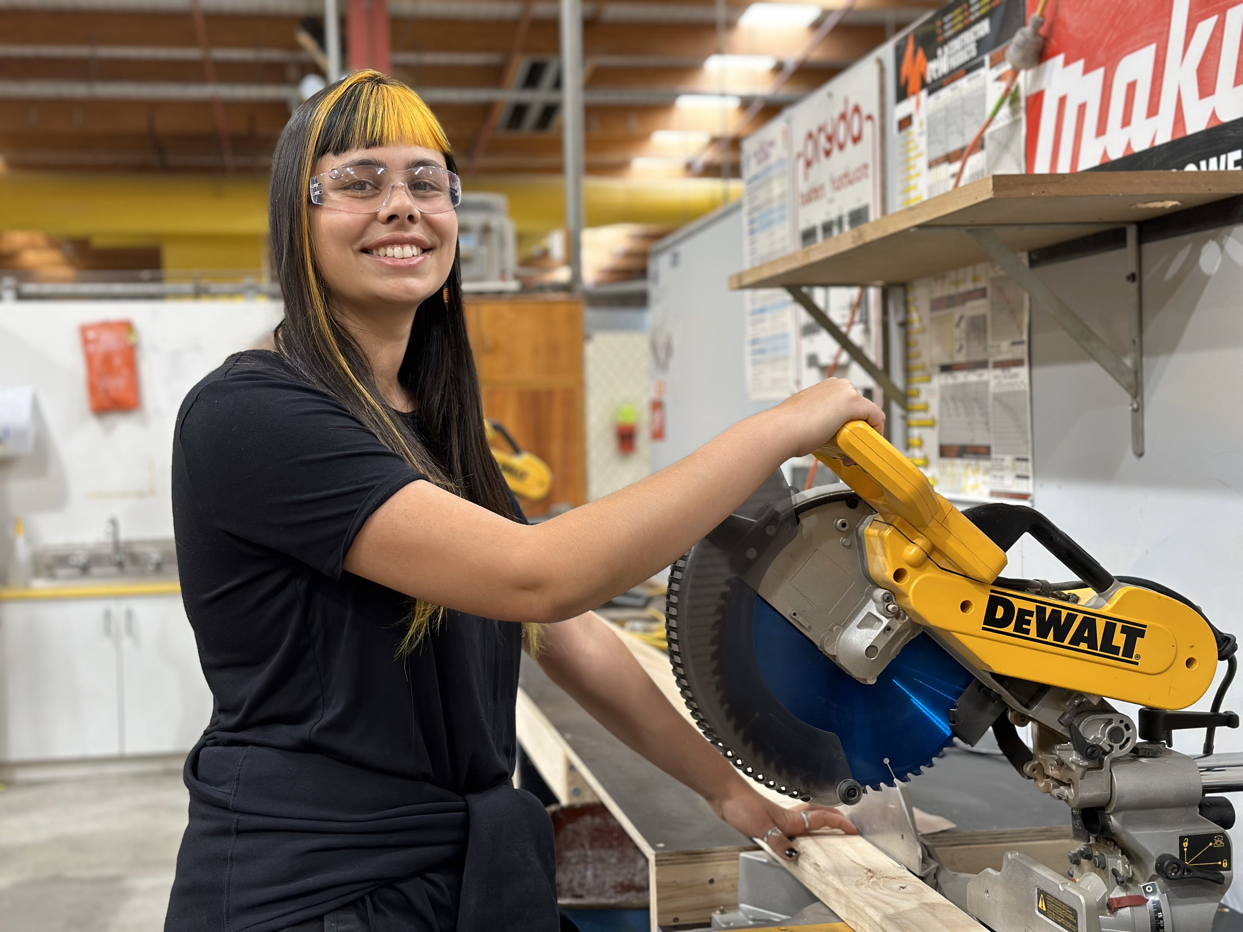 Student Tash Matthews uses drop saw to cut timber