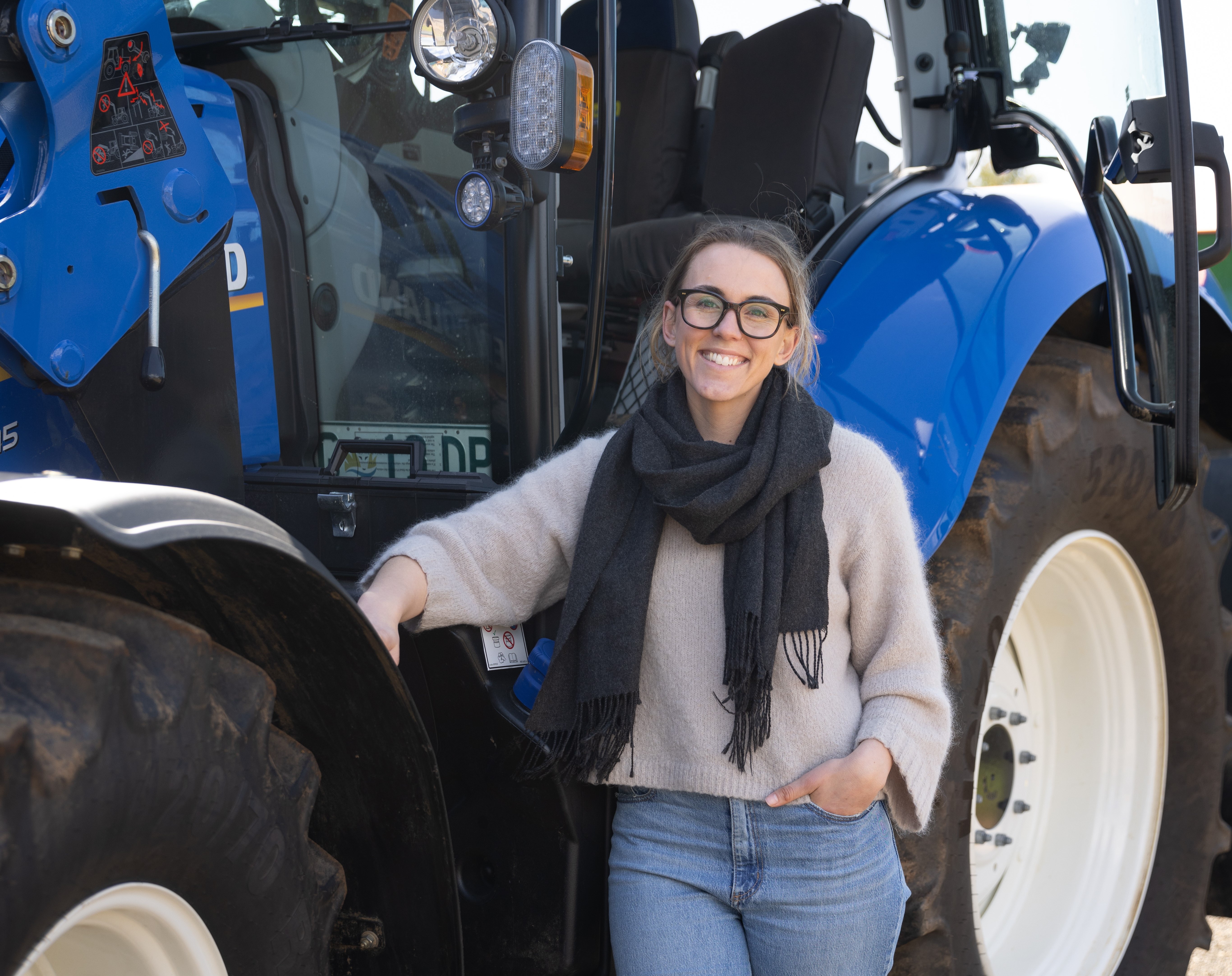Hannah Lewis stands beside blue tractor