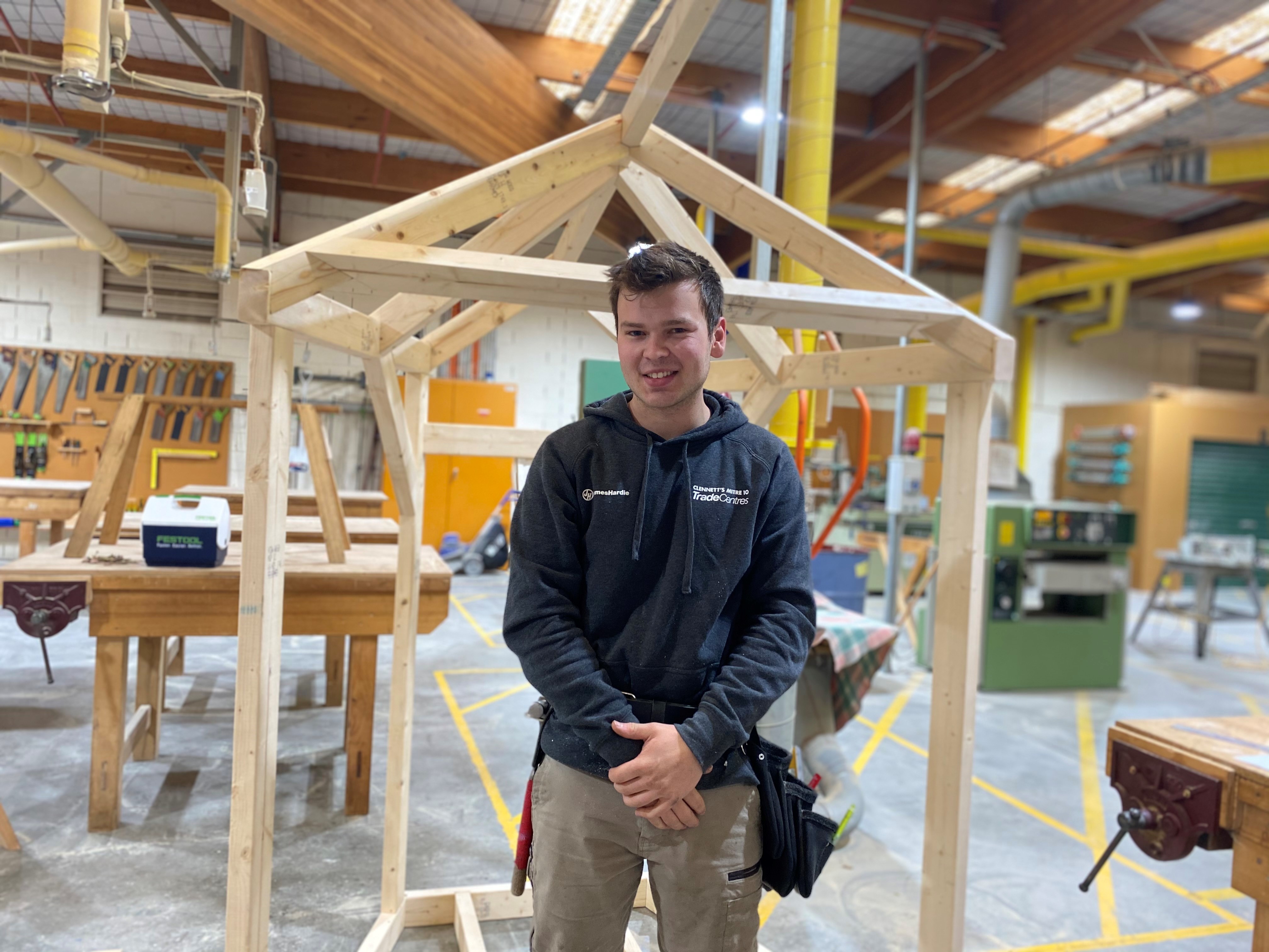 Carpentry student poses for a photo in the workshop