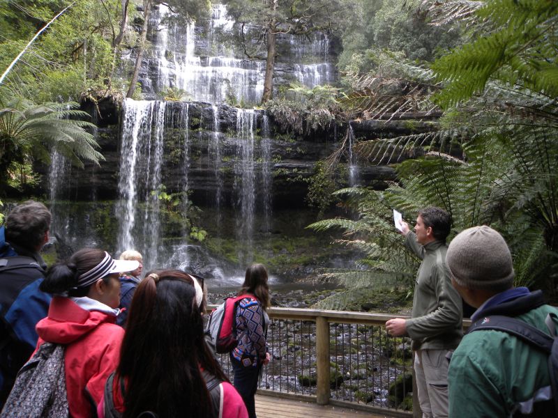 Tour guide and group of people standing in front of a waterfall