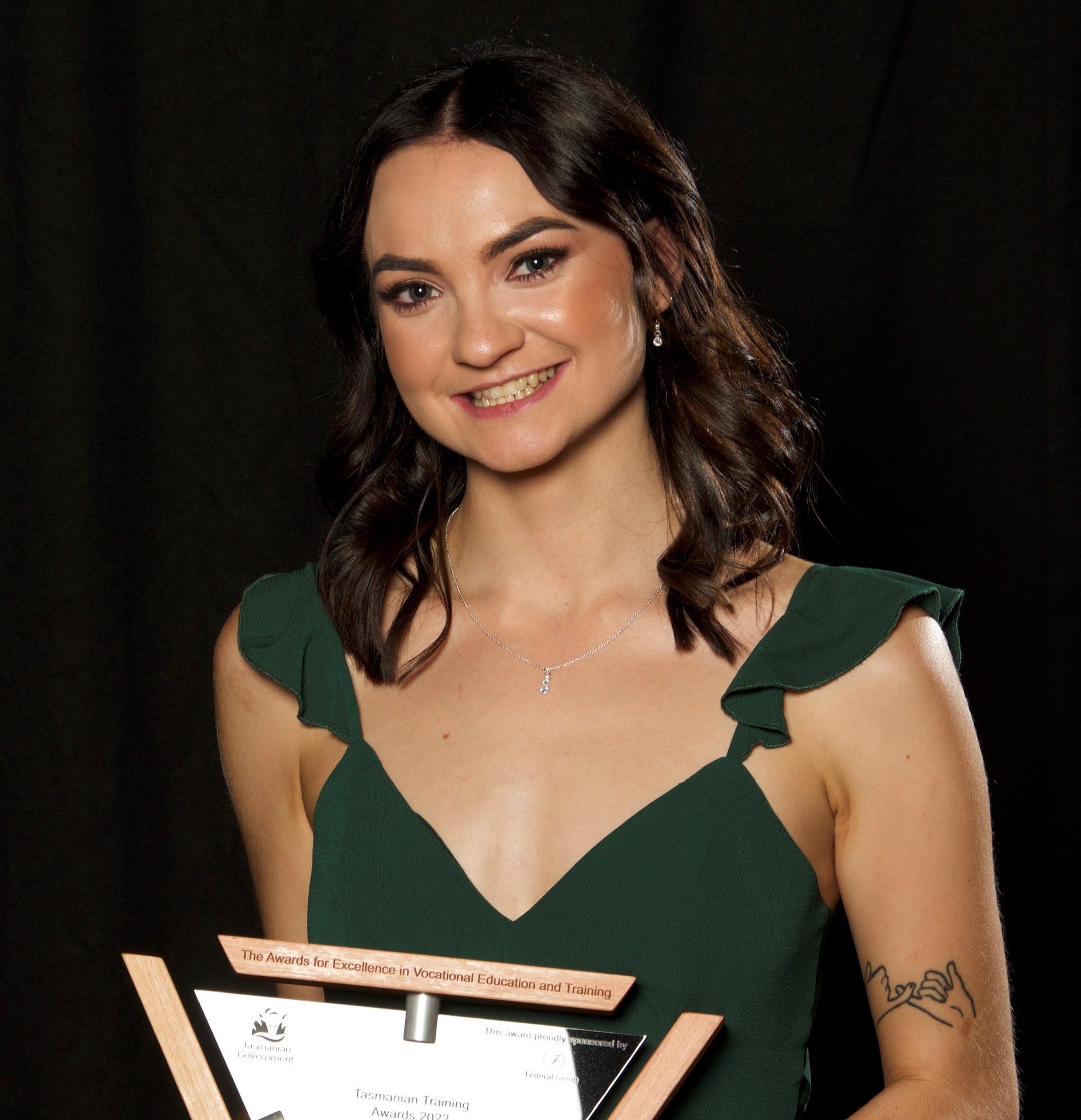 Natasha Robins – Trainee of the Year posing with her trophy sitting on a stool
