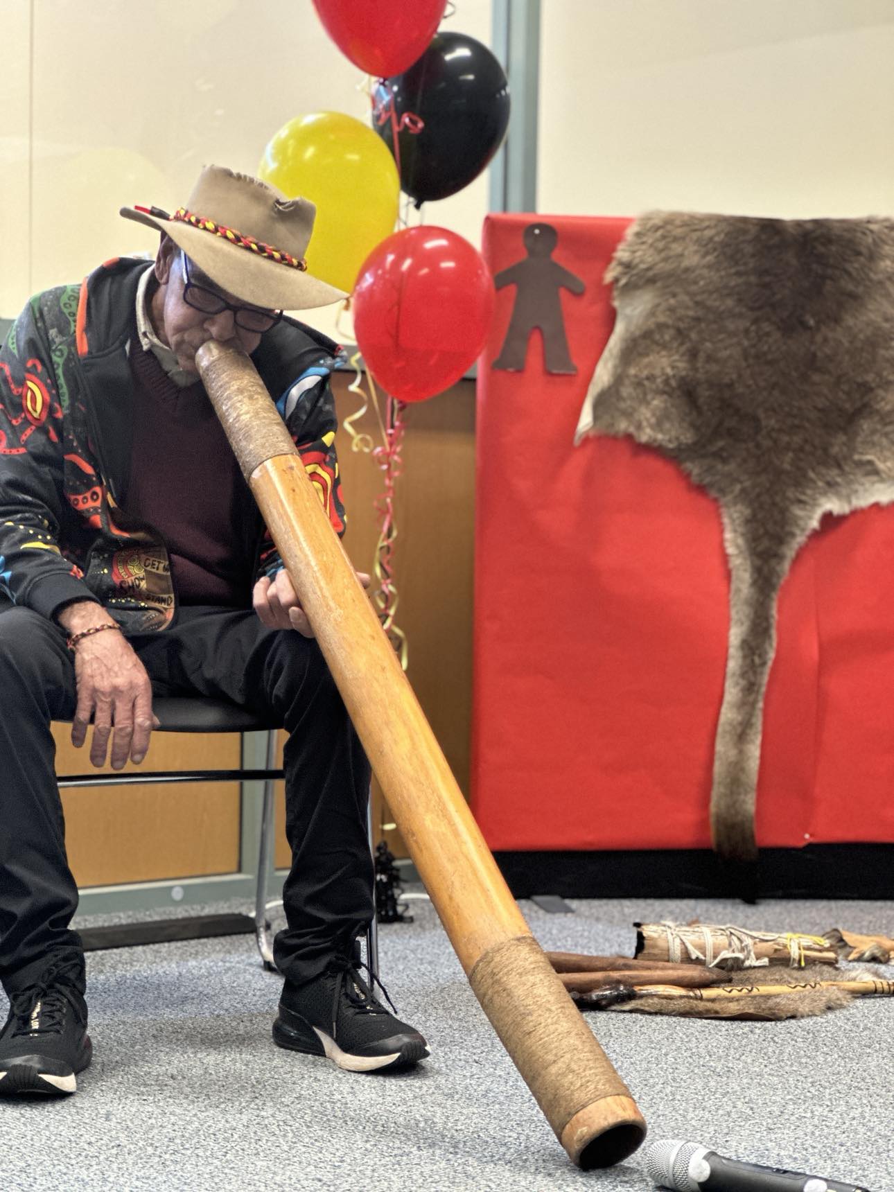 Aboriginal man sitting playing a didgeridoo 