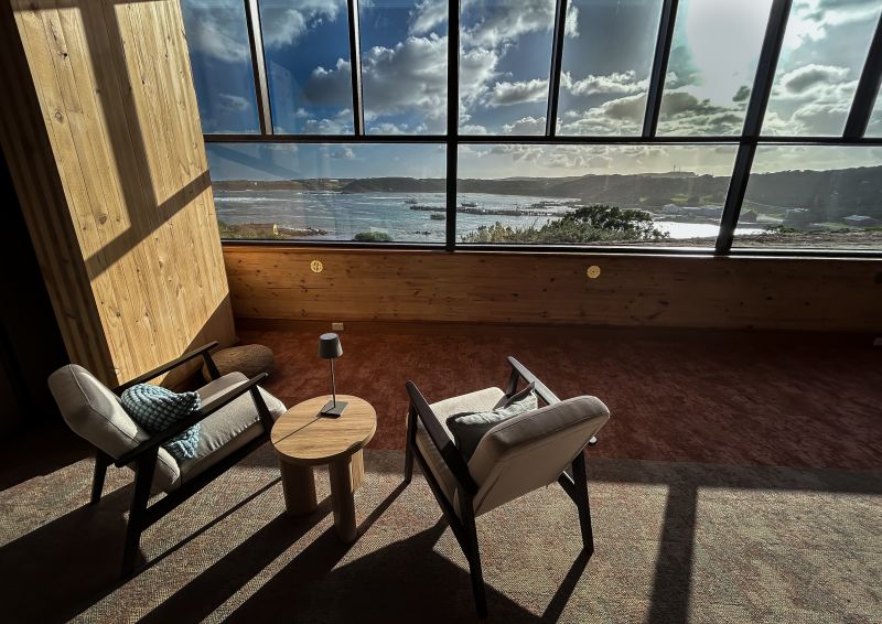 Chairs and a side table in a quiet space looking out over the water