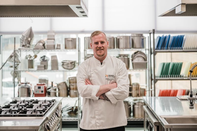 Cookery Teacher in the commercial kitchen with his arms crossed