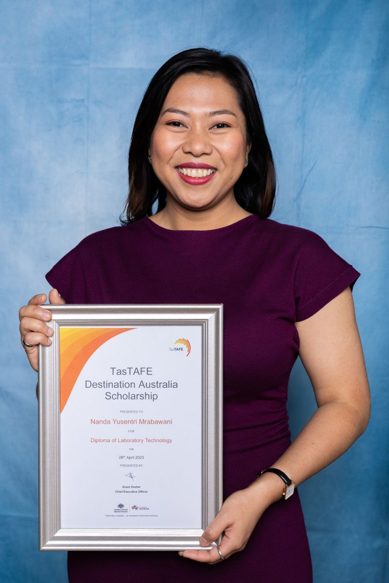 Woman poses with her Destination Australia scholarship certificate