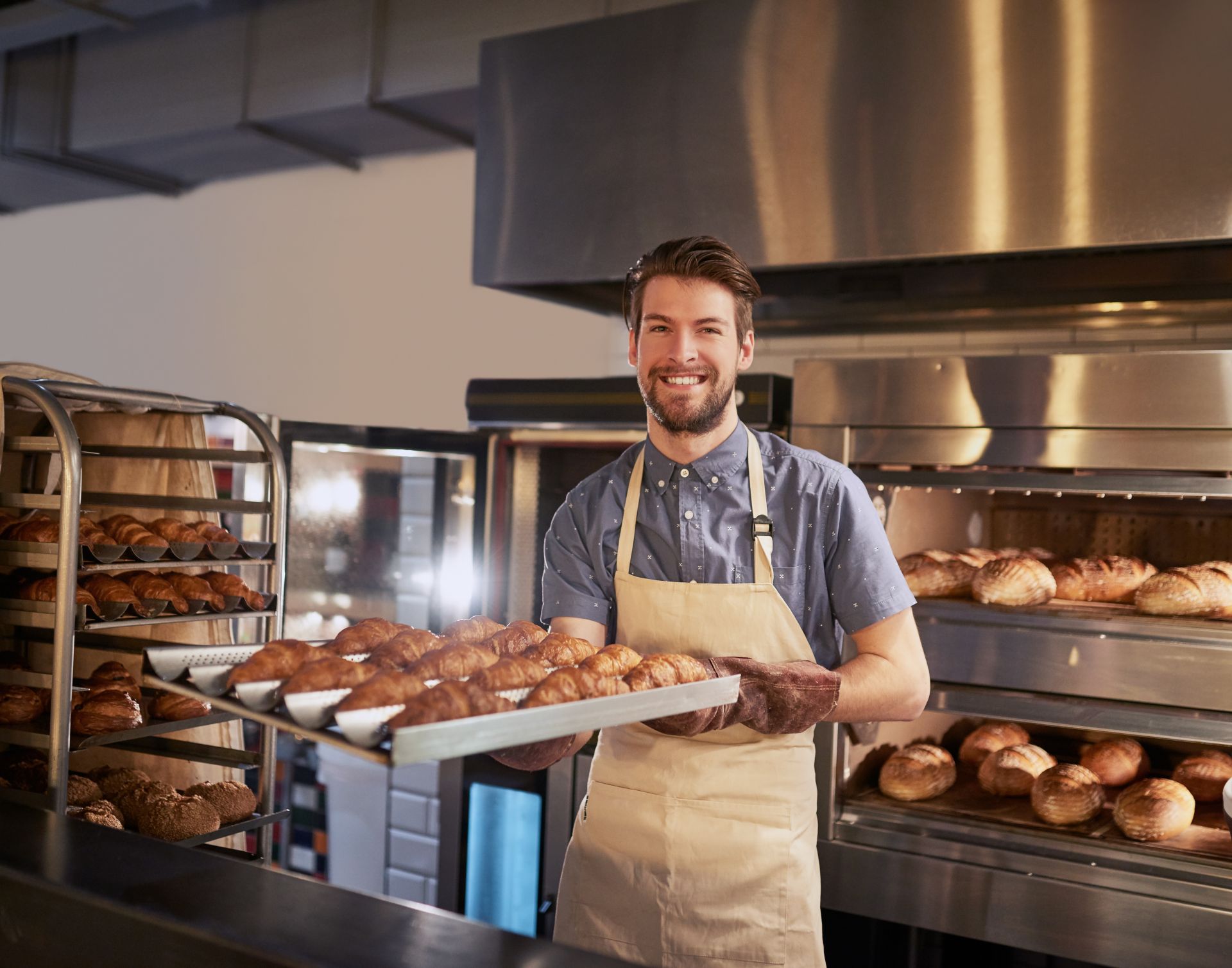 A Baker holding a tray of freshly baked croissants