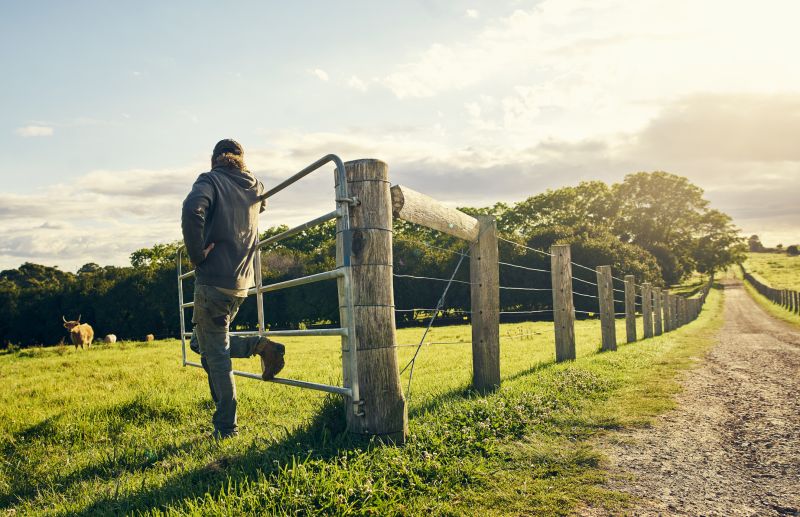 Man leaning on a gate with farm in background