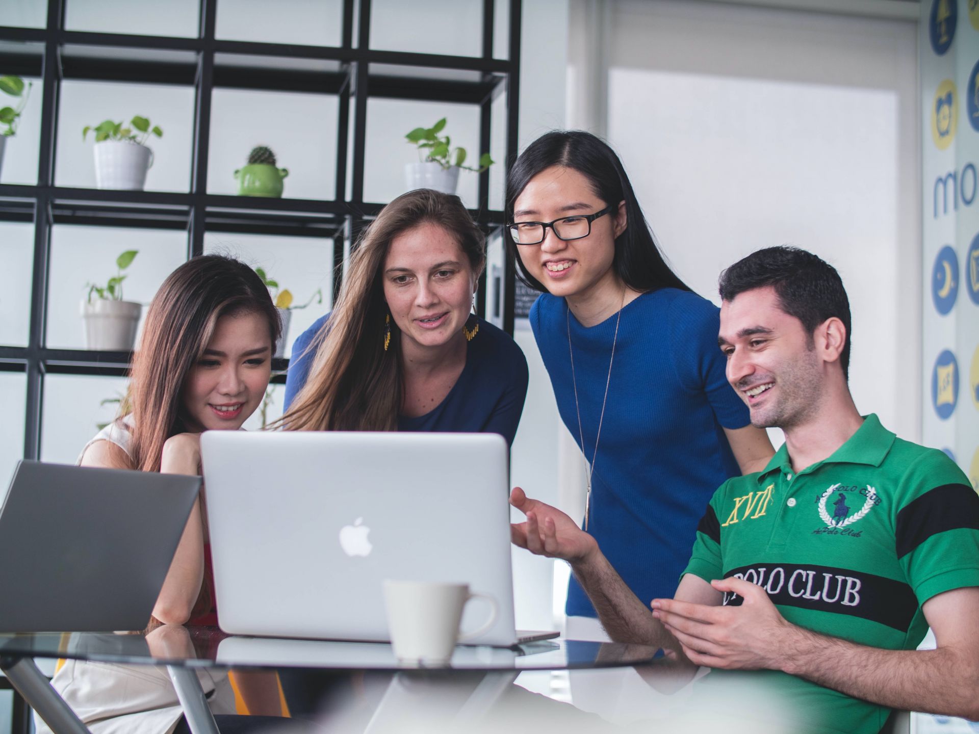 Four students gathered around a laptop