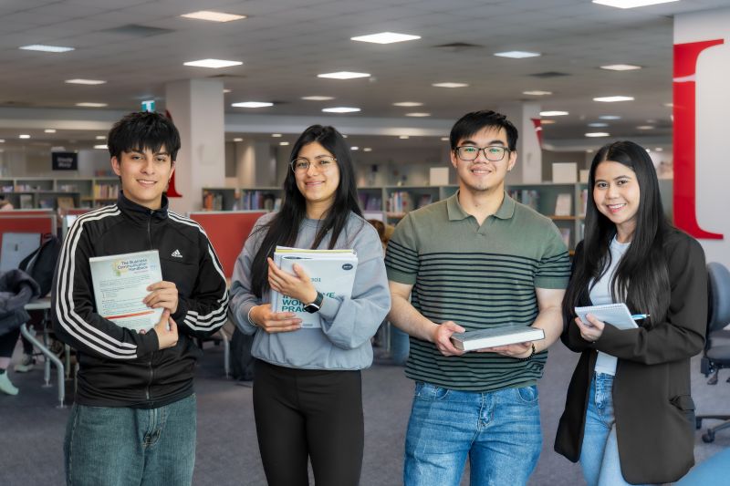 man and woman holding books and notepad in the library