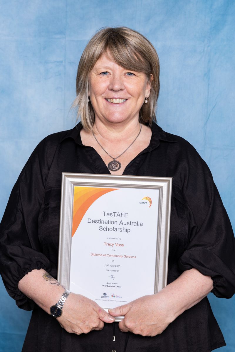 Woman poses with her Destination Australia scholarship certificate