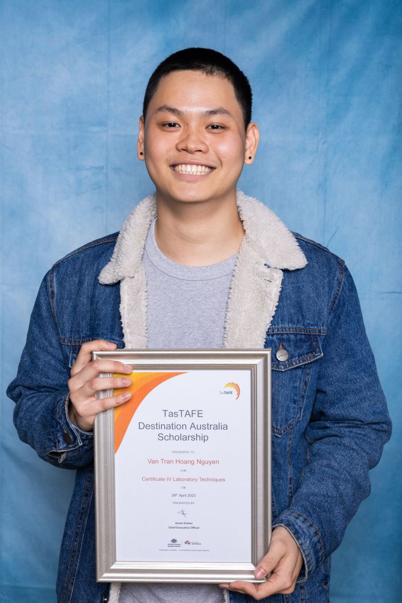 Man poses with his Destination Australia scholarship certificate