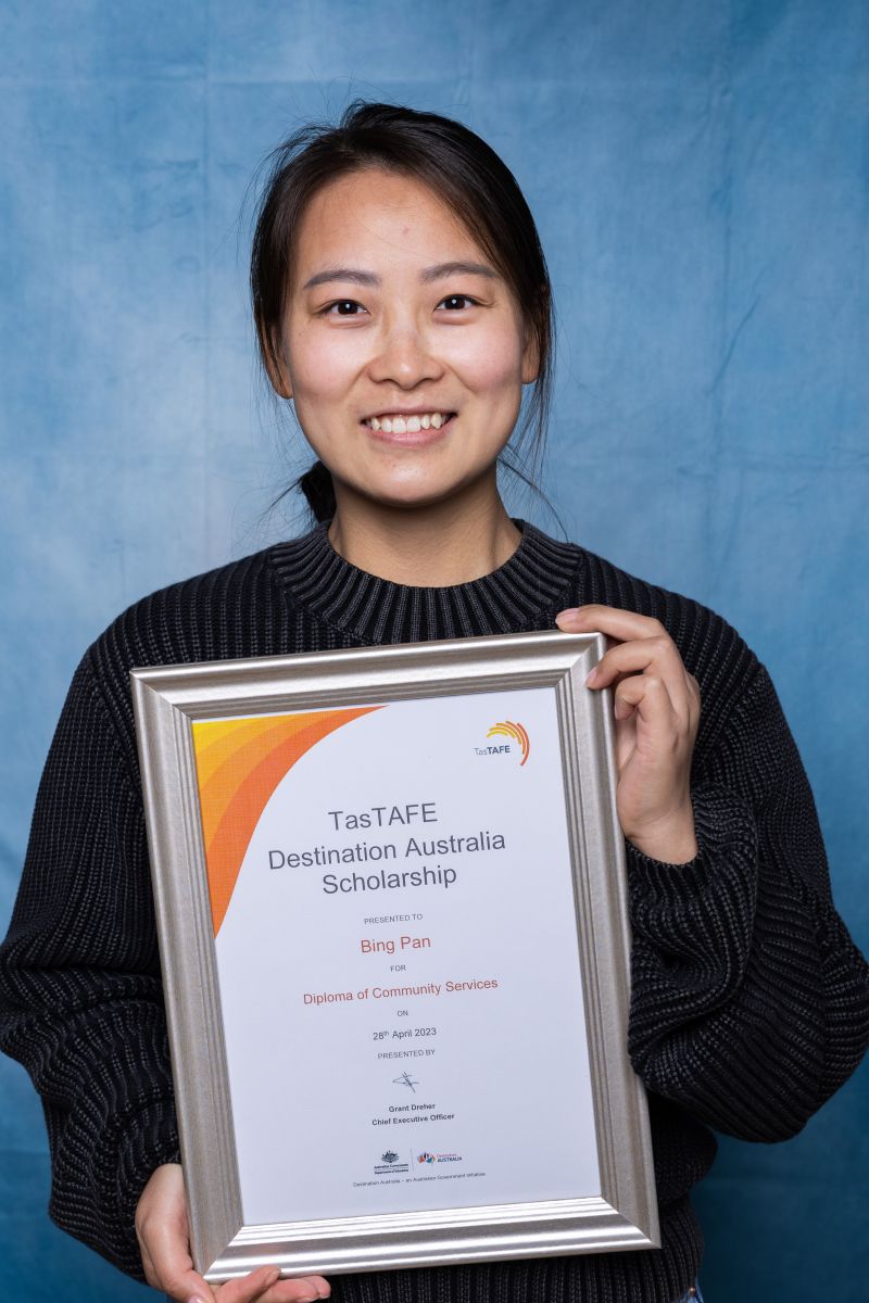 Woman poses with her Destination Australia scholarship certificate