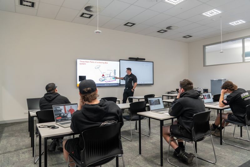 Teacher at the front with students learning in an automotive classroom equipped with AV and VR technology.