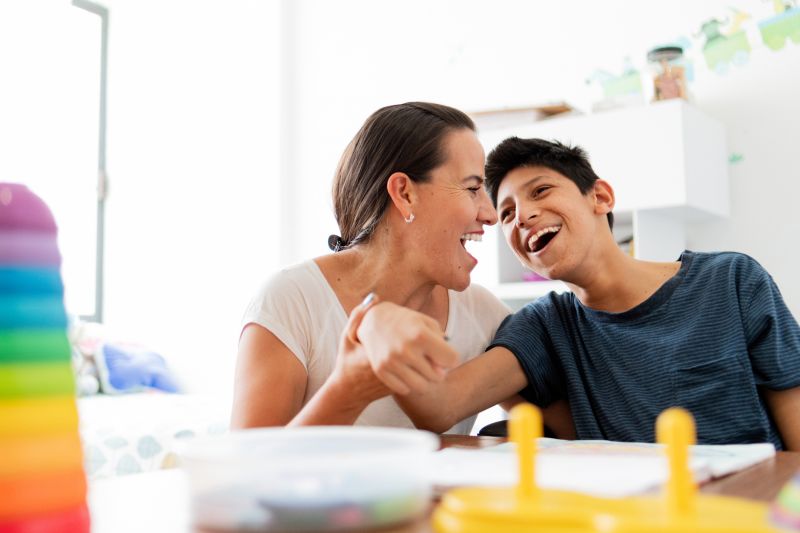 Mother laughing with her you son who has cerebral palsy 