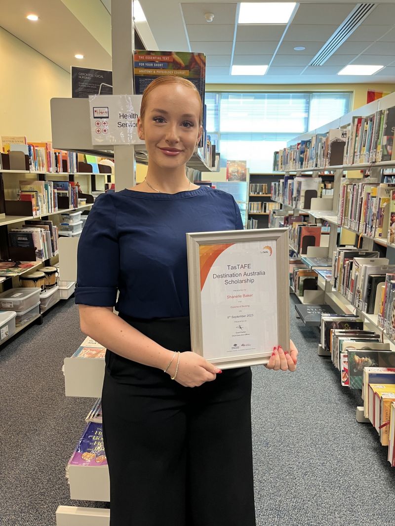 Woman holding a framed certificate in the library