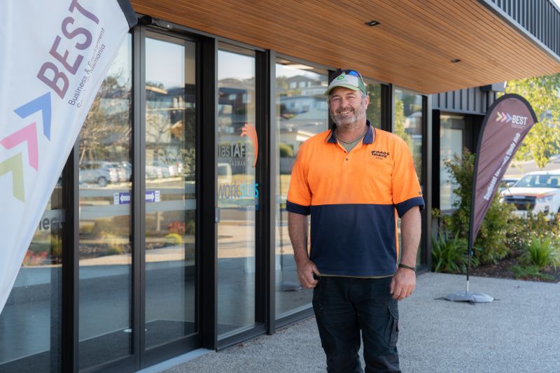 Man wearing orange Hi-Vis t-shirt standing for a photo infront of the South East Training and Jobs Hub which is home to BEST
