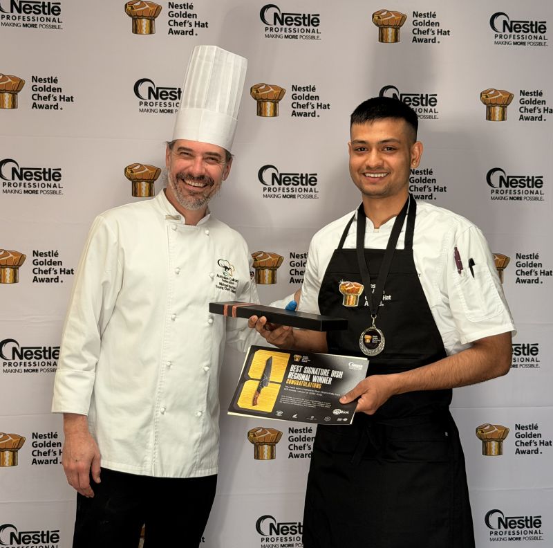 Participant holding the Best Signature Dish Regional Winner award plaque while standing beside a judge at the Nestlé Golden Chef's Hat Award competition.