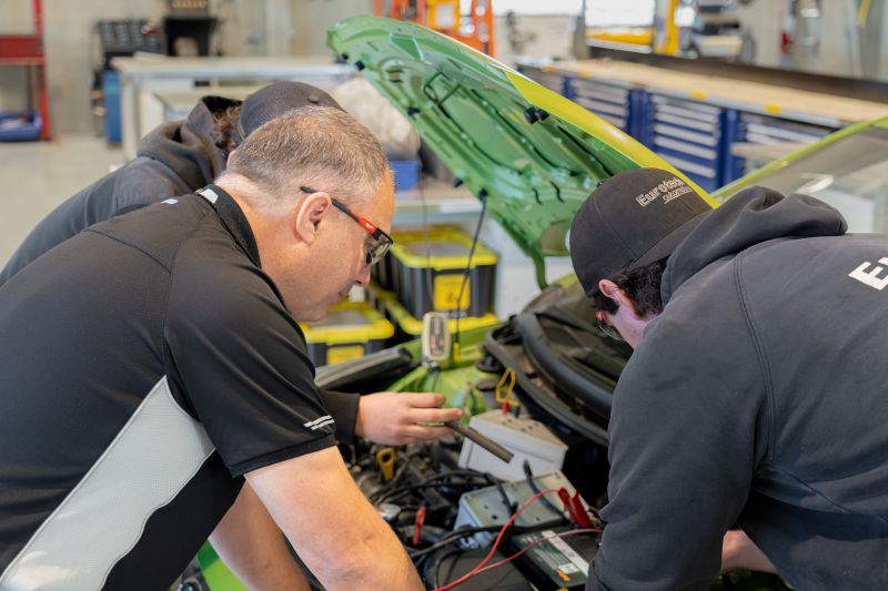 Two learners working on a vehicle engine under instructor guidance in a TasTAFE automotive training workshop