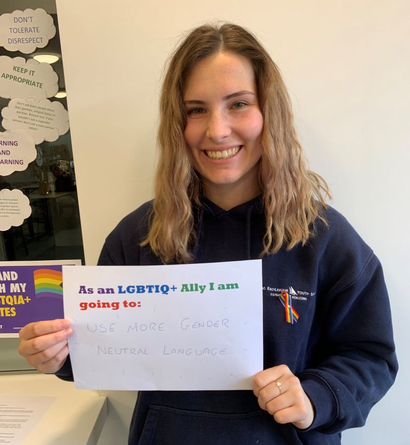 Teacher holding a sign showing support for IDAHOBIT