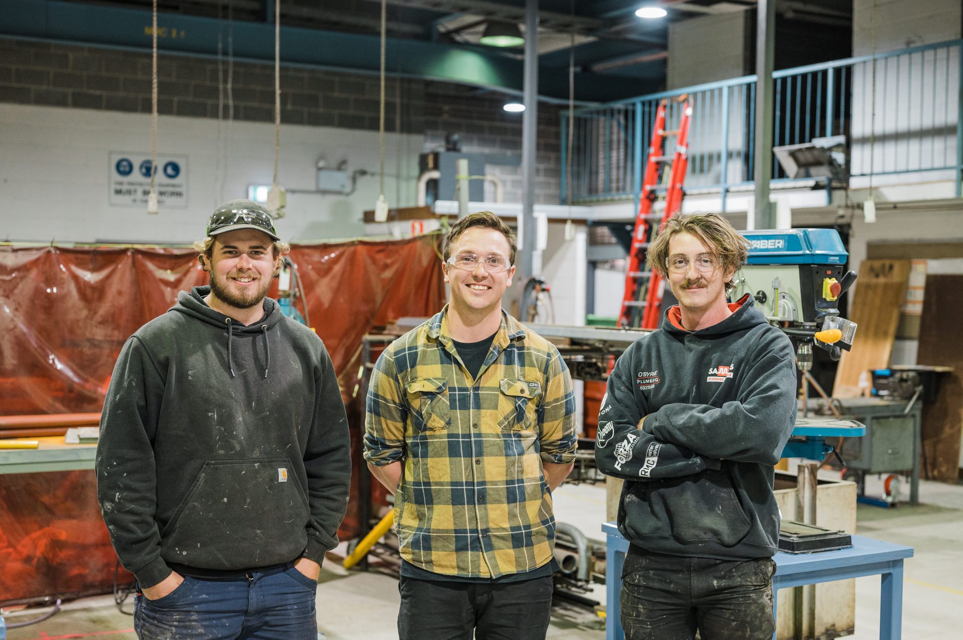 Plumbing teacher standing for a photo with 2 other people in the plumbing workshop