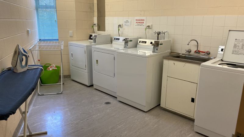 A laundry with washing machines, a sink and an Ironing board