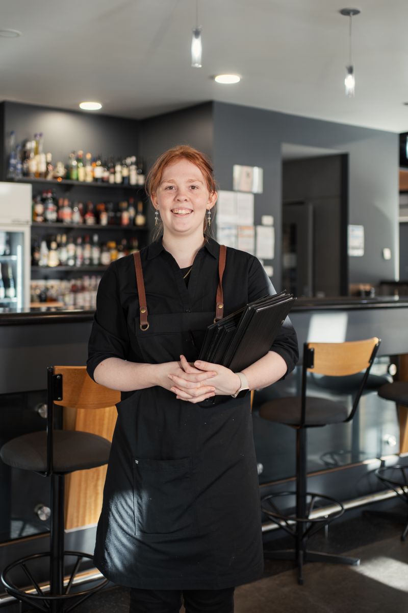 Waitress posing for photo holding menu under arm