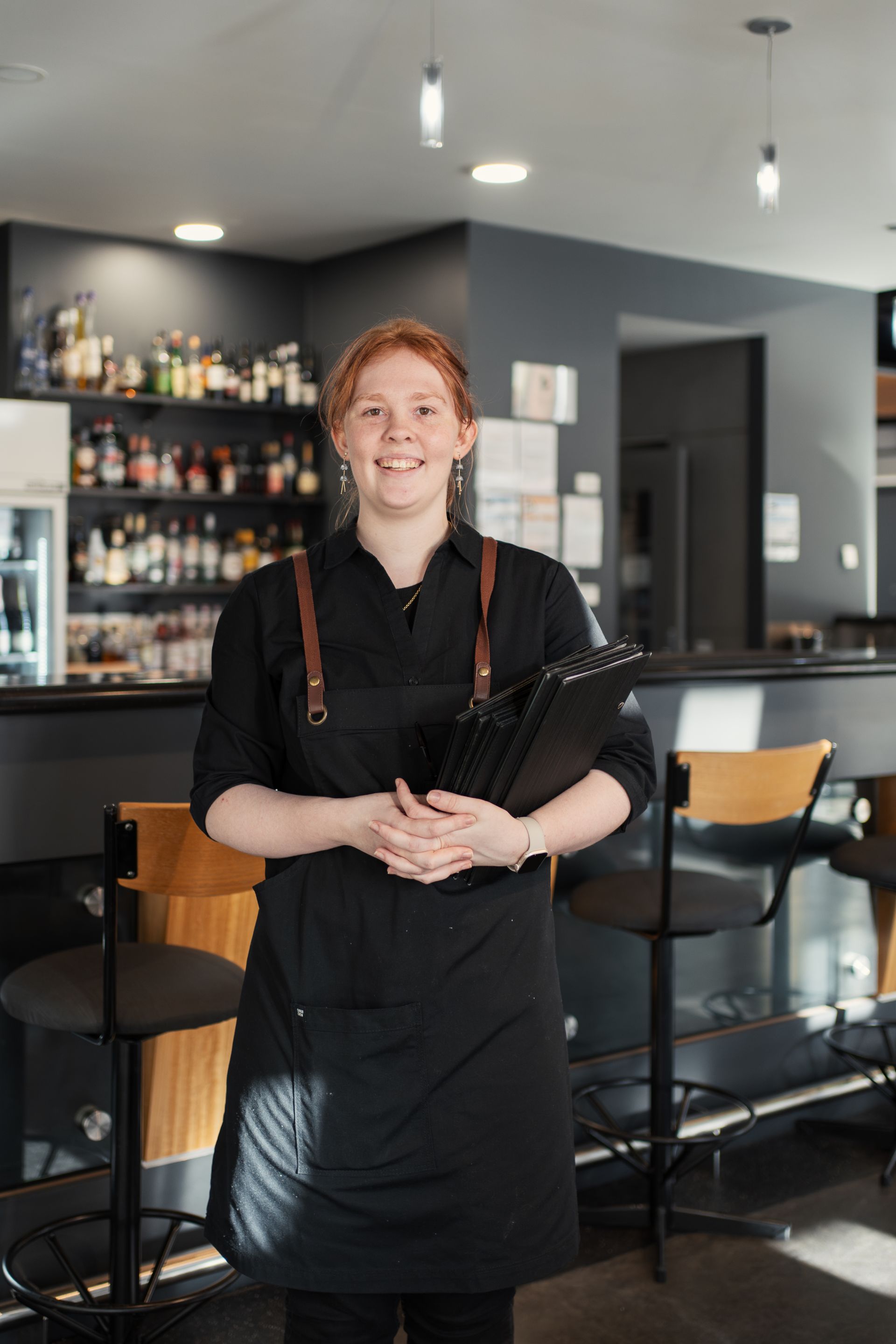 Waitress posing for photo holding menu under arm