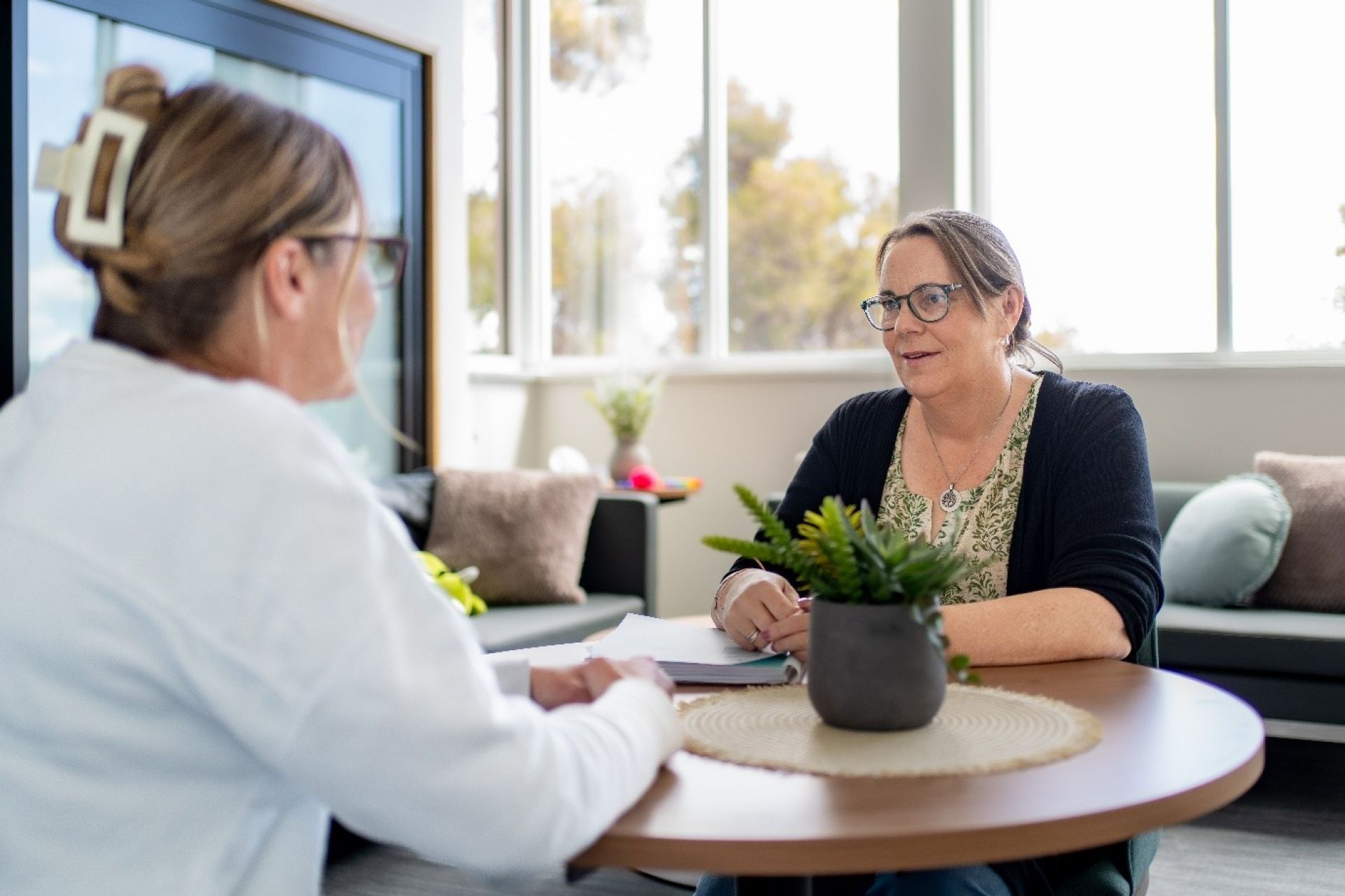 Two women sitting on a round table and engaging in consultation